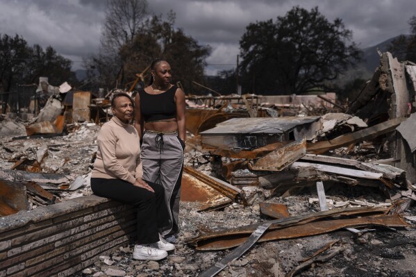 Barbara Shay, left, owner of Little Red Hen cafe, and her daughter, Annisa Faquir, a break for a portrait in front of their business ruins, after being destroyed by the Eaton fire from Altadena, Calif., Friday, March 28, 2025 (AP Photo/Jae C. Hong)